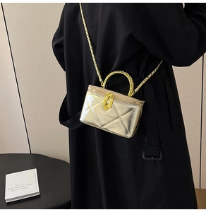 Detail of champagne gold quilted box bag with metal handle and camellia flower zipper pull