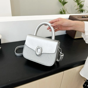 Silver metallic crossbody bag with horseshoe buckle and textured glitter patchwork detail