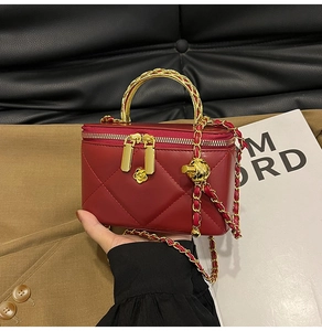 Detail of red quilted mini box bag with gold camellia charm and woven handle