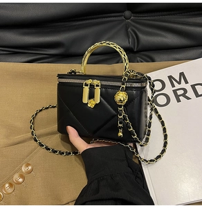 Detailed close-up of a black quilted box bag with golden chain and camellia charm