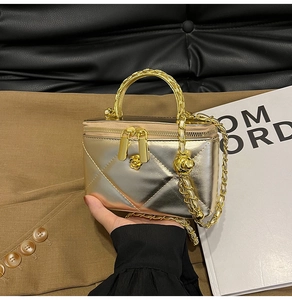 Detail of gold quilted box bag with camellia hardware and woven chain strap