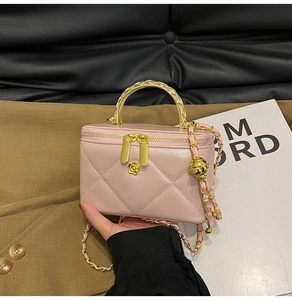 Detailed close-up of pink quilted box bag with camellia zipper pull and chain handle