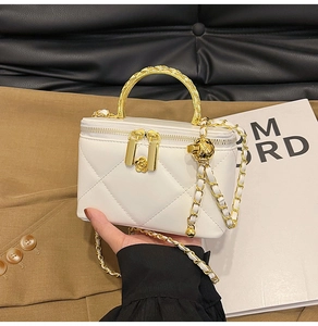 Close-up of white quilted leather box bag with gold chain strap and camellia charm
