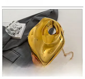 Close-up of a gold sculptural evening bag with a high-gloss metallic finish and fine chain