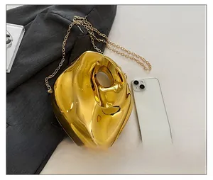 Detail view of a gold metallic irregular handbag with stone texture and chain strap