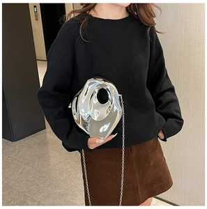 Close-up of irregular silver metallic box clutch with polished mirror finish and chain strap