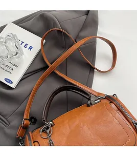 Detailed view of caramel leather Boston bag featuring brown handles and silver chain accents