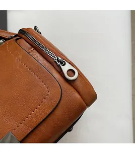 Detailed close-up of polished silver metal zipper puller on a brown leather Boston bag