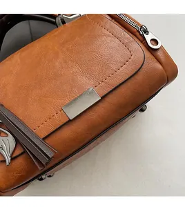 Macro shot of silver zipper, metal hardware, and brown leather tassels on a Boston bag
