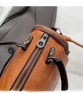 Close-up of smooth metal zipper and brown faux leather texture on Boston bag