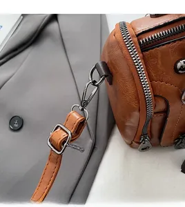 Macro detail of brown lychee grain PU leather bag with dark gunmetal hardware and swivel hooks