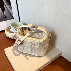 Women straw crossbody bag with white leather straps and gold metal clasp in a lifestyle setting