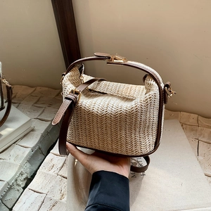Minimalist straw woven handbag with brown leather handles and adjustable shoulder strap