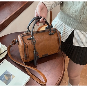 Close-up of vintage brown Boston bag with decorative tassels and feline charm detail