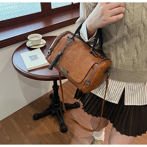 Close-up of vintage brown Boston bag with tassel detail on a wooden cafe table