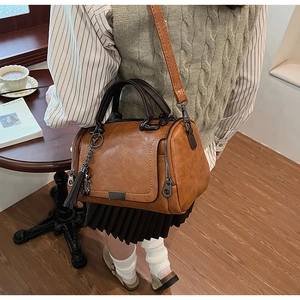 Retro brown Boston bag detail with tassel charm and crossbody strap worn by model