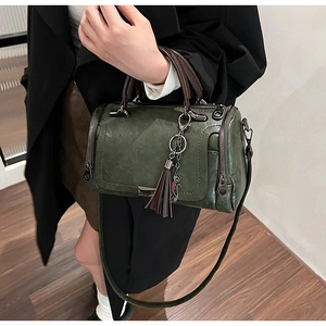 Detailed macro of dark green oil wax leather texture on a retro Boston bag with tassel