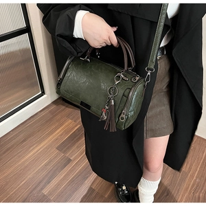Detailed view of vintage green leather Boston bag with tassel and cat charm decoration