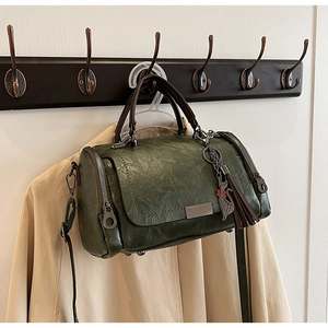 Detail of green vintage Boston bag with fringe tassel and cat charm on wooden hook