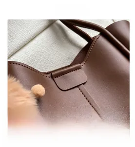 Detailed view of dark brown pebbled leather texture and precision stitching on a tote bag