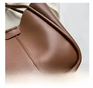 Close-up of premium brown leather texture and stitching on a large tote bag