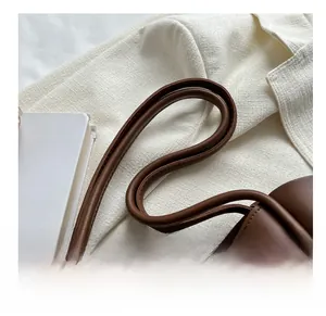 Detail of brown leather tote bag with sturdy round handles and gold metal rings