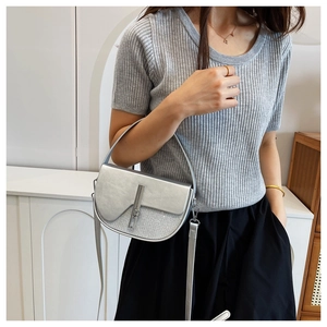 Detailed view of silver saddle bag with metallic finish and magnetic snap closure