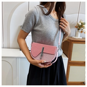 Detailed view of pink leather saddle bag with silver vertical buckle on a model