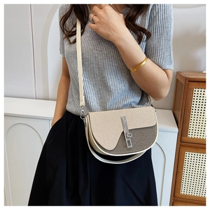 Detail of saddle crossbody bag showing beige twill and brown woven fabric with silver clasp