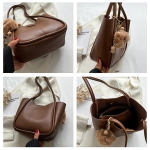 Brown leather tote bag featuring a plush pom-pom charm and spacious interior compartments