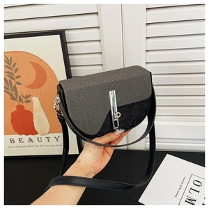 Detail of grey and black half-moon shoulder bag with metallic rectangular twist lock