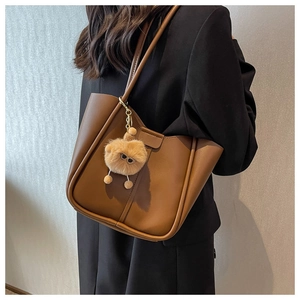 Brown leather tote bag for women with a cute plush charm accessory for commuting