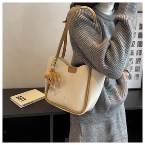 Minimalist cream tote bag featuring brown edge finish and a plush animal charm