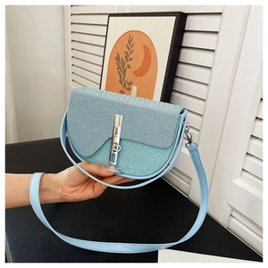 Detail of light blue saddle bag featuring woven texture flap and silver metal lock closure