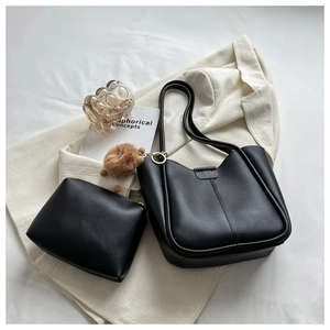 Detail of black faux leather tote bag set with matching pouch and brown plush charm