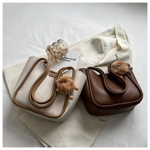 Detail of cream and coffee tote bags with U-shaped stitching and plush sunglass charms