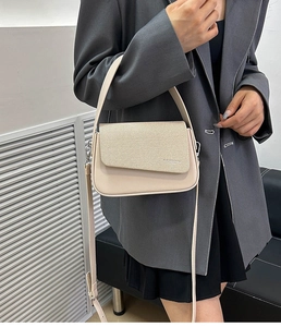 Detail of beige flap crossbody bag featuring textured fabric and smooth synthetic leather