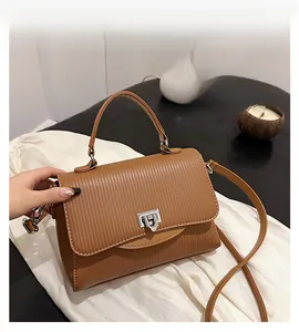 Detail of brown striped leather handbag with metal buckle and elegant shoulder strap