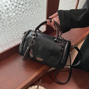 Vintage black cylinder Boston bag with tassel charm and sleek metallic zipper accents
