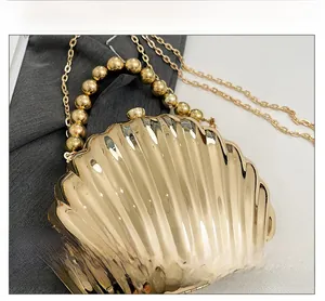 Detailed view of golden shell evening bag with radial texture and metal bead handle