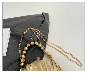 Macro detail of golden shell evening clutch with beaded handle and fine chain strap