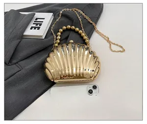 Detailed close-up of shell-shaped gold acrylic evening bag with wave texture and bead handle