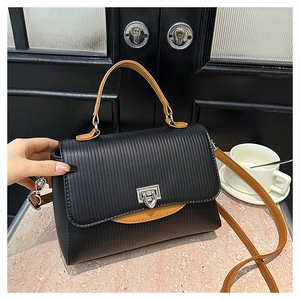 Detail of two-tone handbag with black embossed texture and contrast tan shoulder strap