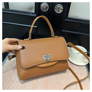Detailed view of caramel handbag with vertical pleats and silver metallic twist lock