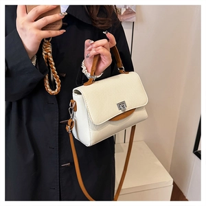 Detail of cream leather shoulder bag with brown handle and silver rotating lock