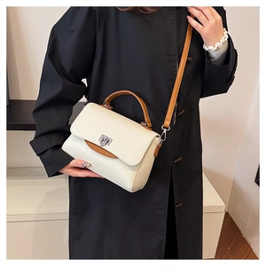 Detail of cream crossbody bag featuring vertical texture and silver metal twist lock