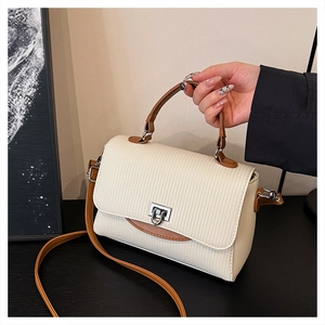 Detail of cream handbag showing vertical embossed texture and silver metal twist lock