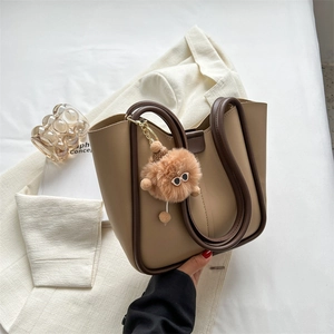 Retro khaki leather tote bag with brown cylindrical handles and plush puppy charm