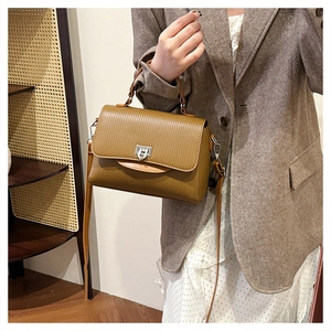 Detail of caramel tote bag with vertical stripes and silver metallic twist lock closure