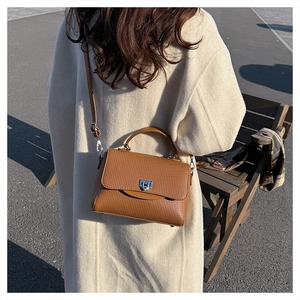 Detailed shot of caramel brown pleated leather bag with silver metallic square lock closure